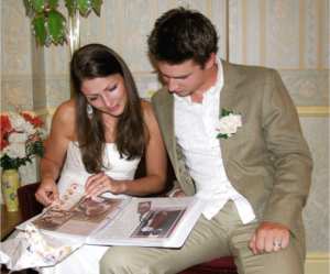 the bride and groom looking through their wedding day scrapbook